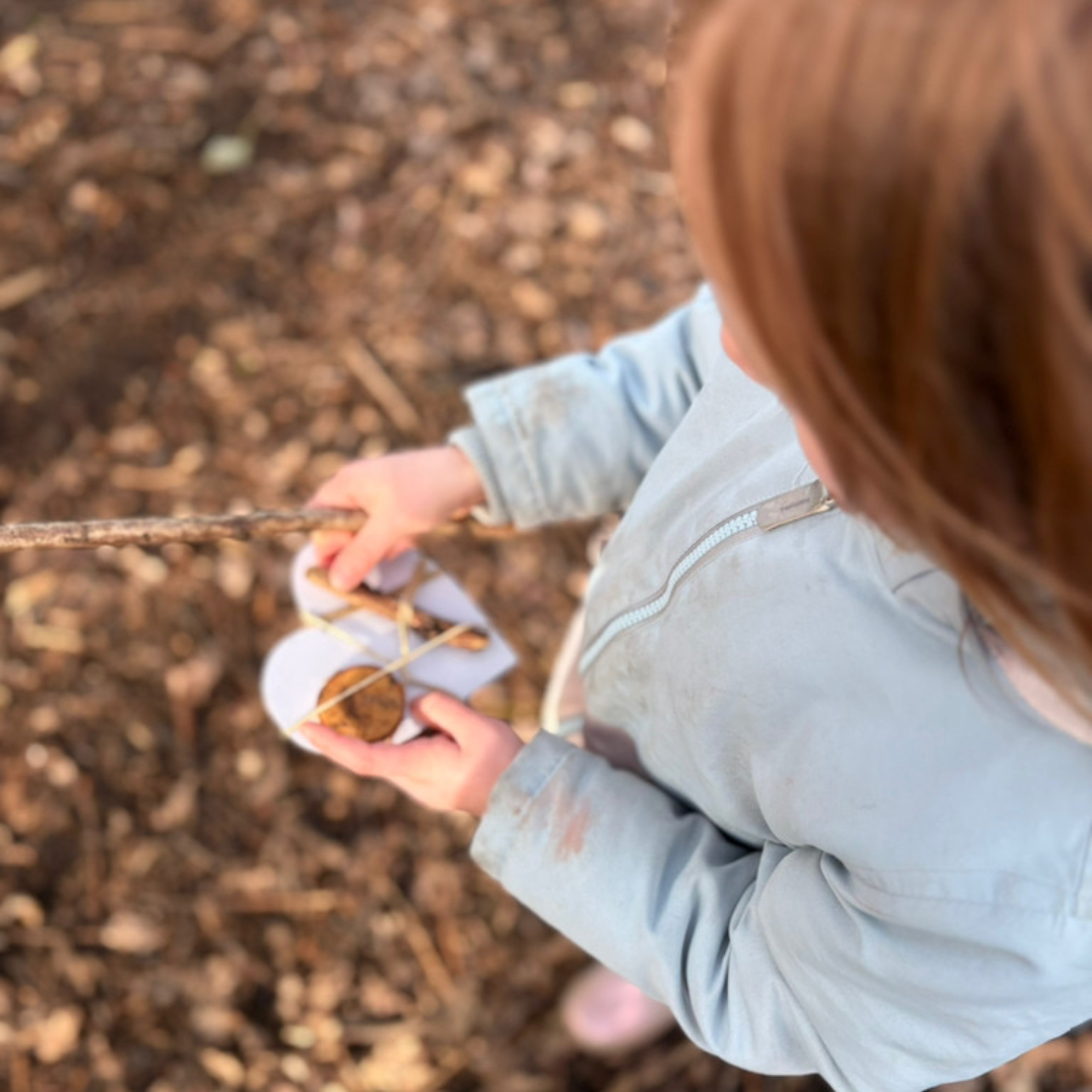 a child exploring an outside woodland area, putting natural objects onto a heart shape